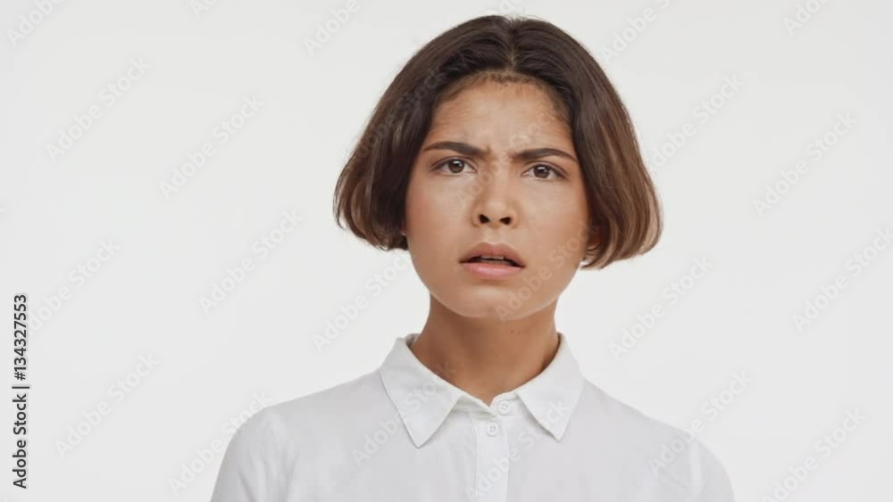 Young beautiful brunette east asian female in shirt frighting and disapproving on white background in slowmotion Young beautiful brunette east asian female in shirt frighting and disapproving on white background in slowmotion