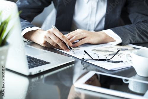 Businesswoman reading newspaper on worktable