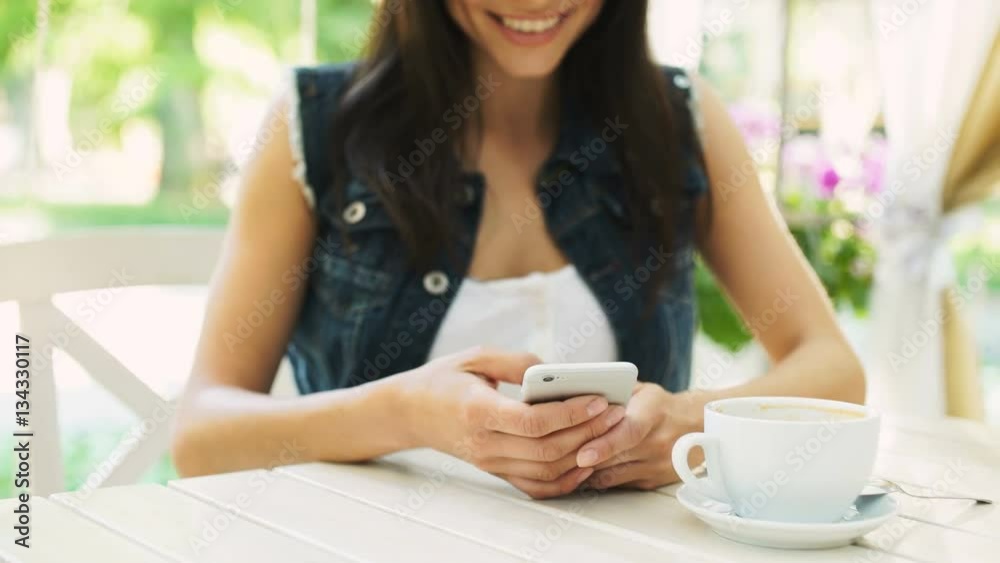 Young smiling woman texting message on mobile phone while sitting in cafe Young smiling woman texting message on mobile phone while sitting in cafe