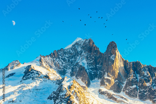 Beautiful mountains. The top of the mountain, moon and the birds. Ski resort in Chamonix Grands Montets, French Alps, France, Europe.