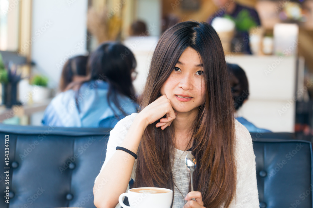 Asian women sitting in library with cup of coffee to make a idea Asian women sitting in library with cup of coffee to make a idea