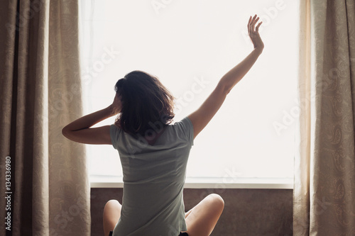 Fototapeta Naklejka Na Ścianę i Meble -  Woman stretching in bed after waking up, back view