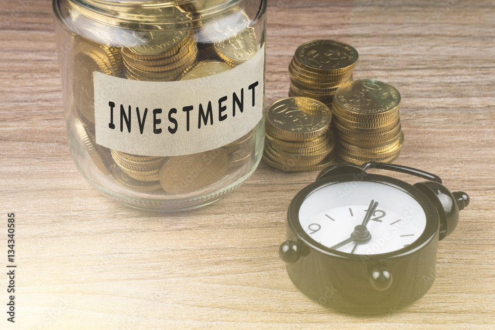 Coins in glass with INVESTMENT label on wooden background. Financial concept. Coins in glass with INVESTMENT label on wooden background. Financial concept.