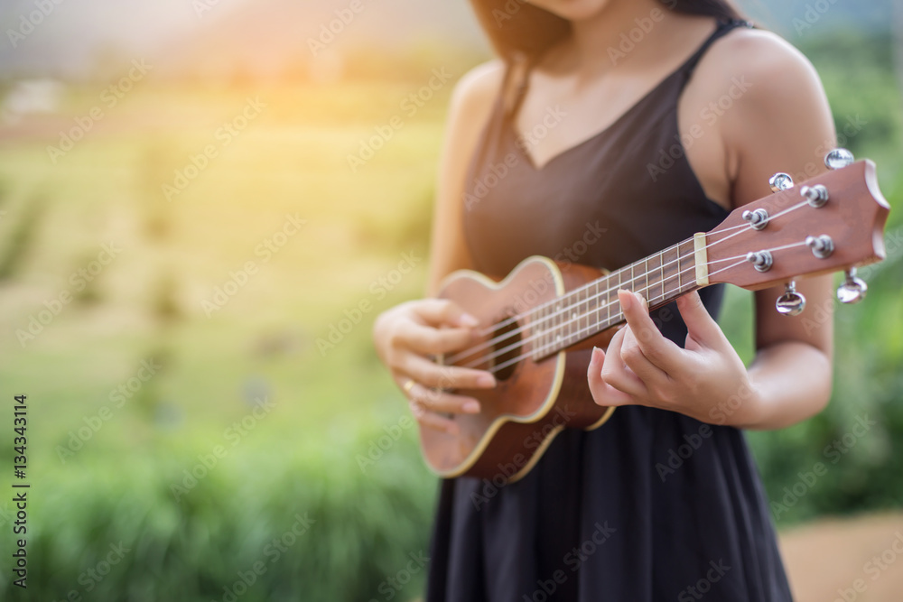 Fototapeta premium Beautiful woman holding a guitar on his shoulder, Nature park su