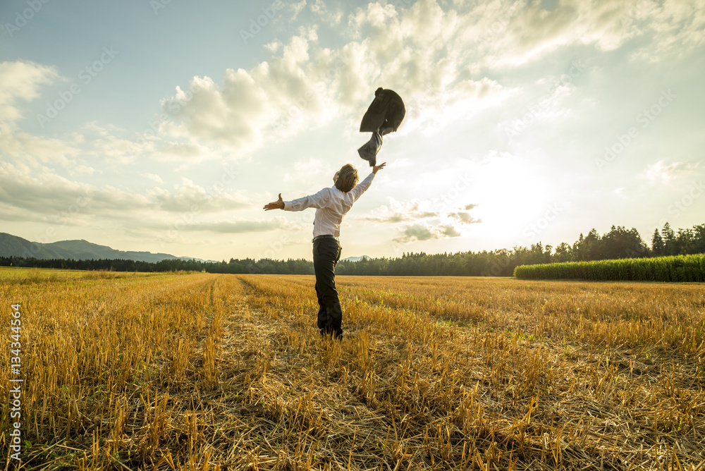 Businessman in field throwing jacket in air Businessman in field throwing jacket in air