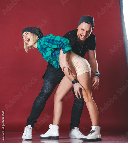 Beautiful young couple in the studio. Girl and guy having fun and laughing.