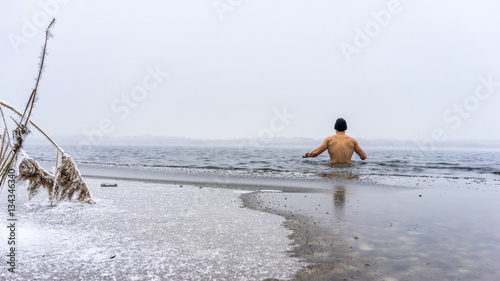 Junger Mann mit Mütze geht Eisbaden photo
