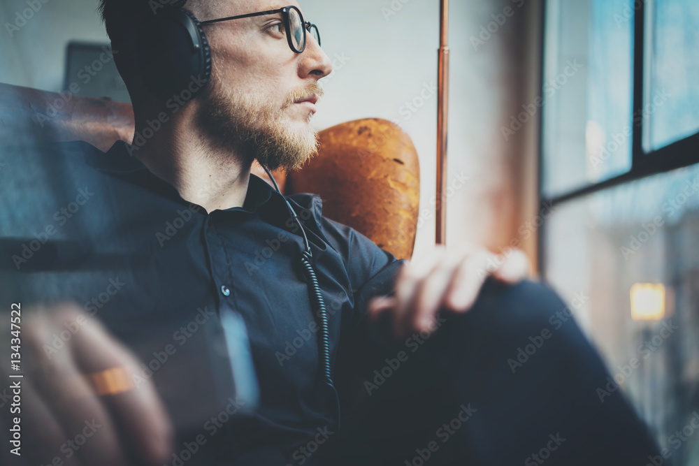 Φωτογραφία Closeup portrait handsome bearded man in headphones listening to music via mobile phone at modern loft