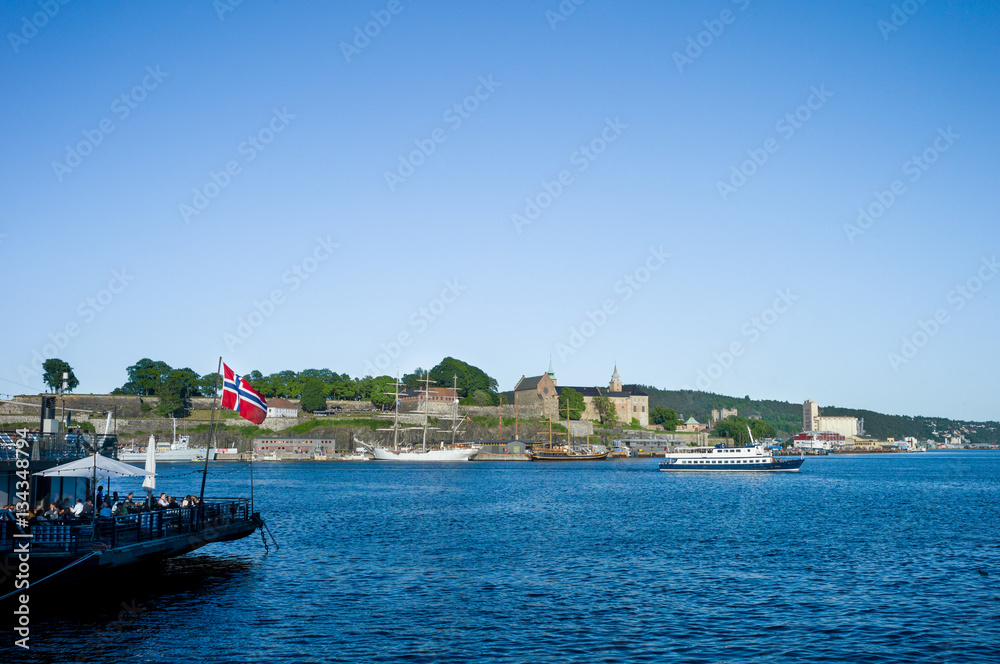 Oslo harbour. Aker Brygge. Boats near Akershus Castle. Norwegian flag