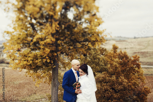 Wedding couple enjoys moment of peace standing before autumn tre © syrotkin