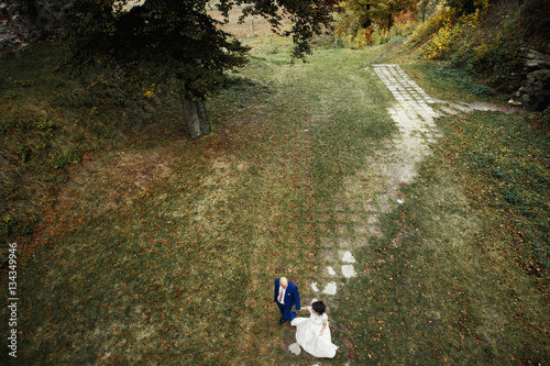 Bride and groom walk along forgotten path in park