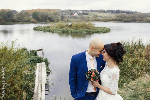 Dreamy wedding couple stands befoe the reed in lake photo