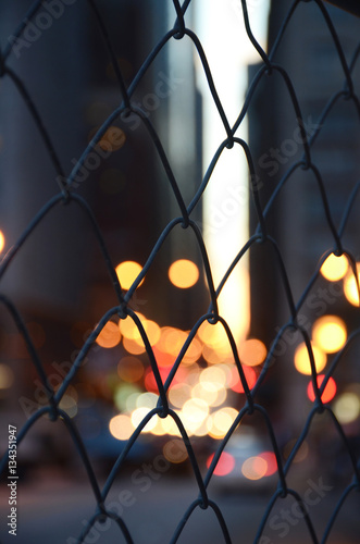 Blurred lights of cars staying in traffic jam. Night city through mesh. Chicago. Autumn 2015