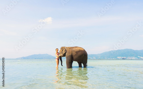 Happy girl and elephant in the sea. Tropical vacation.