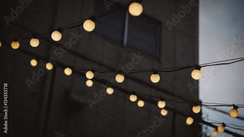 Light Bulbs hanging on a wire with blurred building at During the early evening time, selective focused.