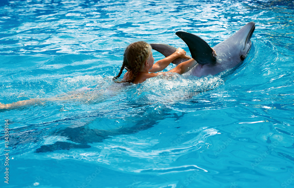 Obraz premium Happy child and dolphins in blue water. Dolphin Assisted Therapy