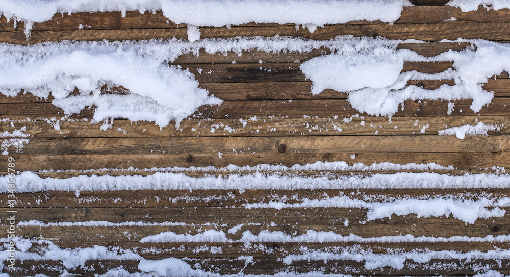 Stacked wooden boards covered with snow