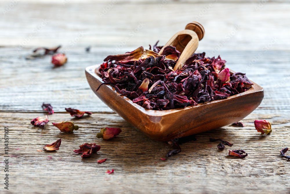 Petals of hibiscus tea in a wooden bowl. - obrazy, fototapety, plakaty 