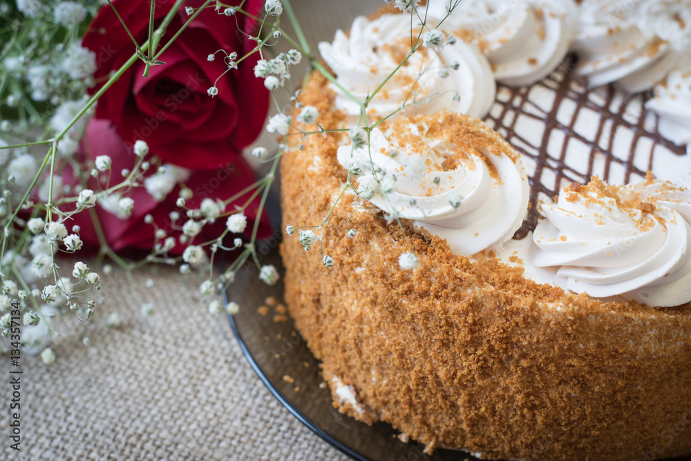 Honey cake with flowers and tea on the table, covered with burlap.