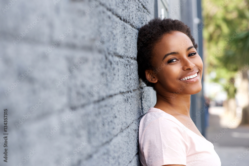 smiling black girl leaning against wall