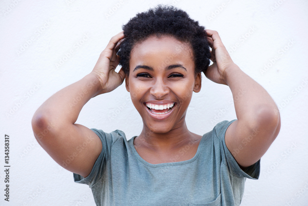 young woman laughing with hands in hair against white background young woman laughing with hands in hair against white background