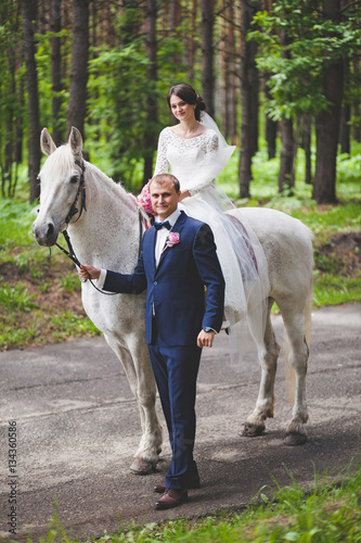 Young groom and bride with horse in park