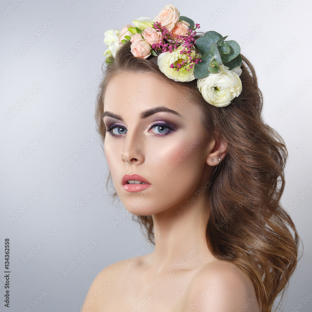 Delicate spring beauty portrait of a beautiful girl with a wreath of flowers on his head isolated on a gray background.