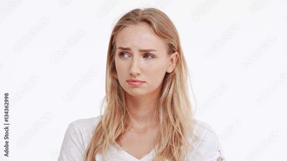 Sad young beautiful Caucasian blonde girl trying not to cry on white background in slowmotion Sad young beautiful Caucasian blonde girl trying not to cry on white background in slowmotion