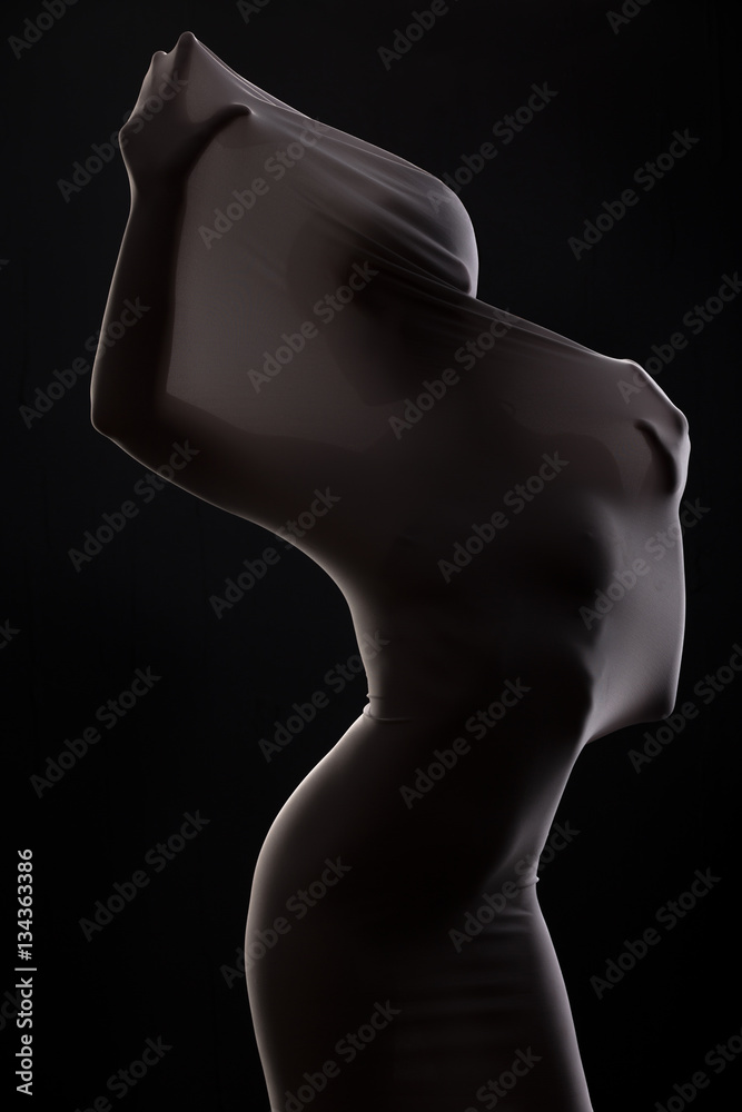 silhouette of woman through  cloth in dark studio