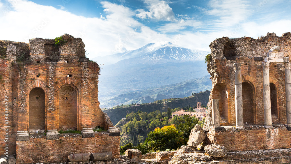 Ruins and columns of antique greek theater in Taormina and Etna Mount in the background. Sicily, Italy, Europe.