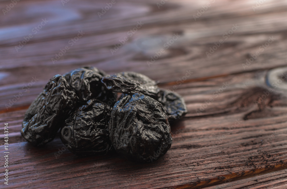 Dried plums (prunes) on the wooden table dark textural Dried plums (prunes) on the wooden table dark textural