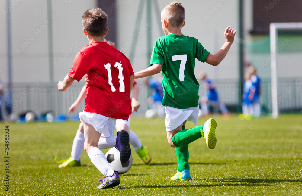 Obraz premium Little boys playing football soccer game on sports field. Football tournament for kids
