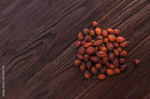 Dried rosehips dark textural wooden table