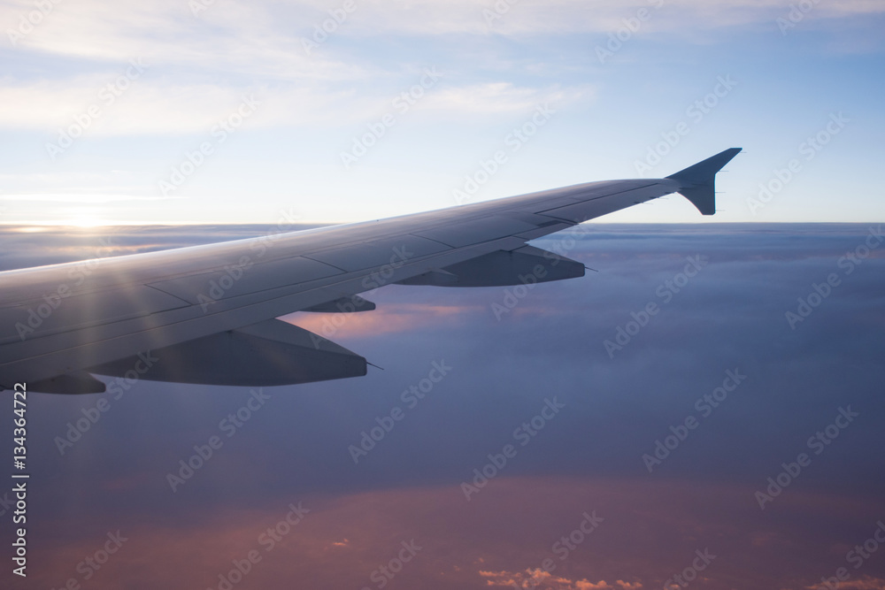 View of airplane wing above beautiful cloud at sunbeam and sunse View of airplane wing above beautiful cloud at sunbeam and sunse