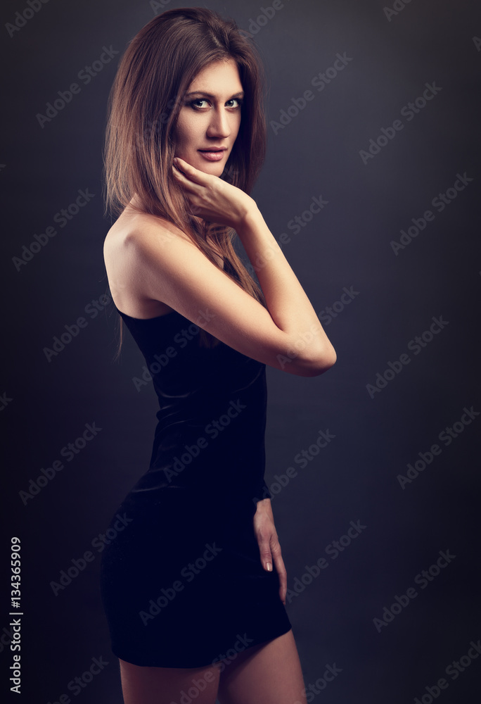 Sexy figure slim model posing in black dress on dark grey backgr Sexy figure slim model posing in black dress on dark grey backgr