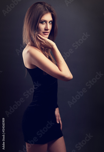 Sexy figure slim model posing in black dress on dark grey backgr