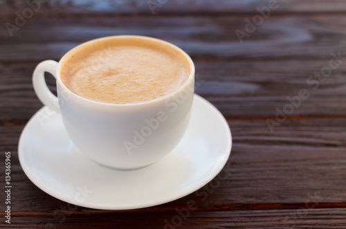 White porcelain cup of coffee on wooden table textural