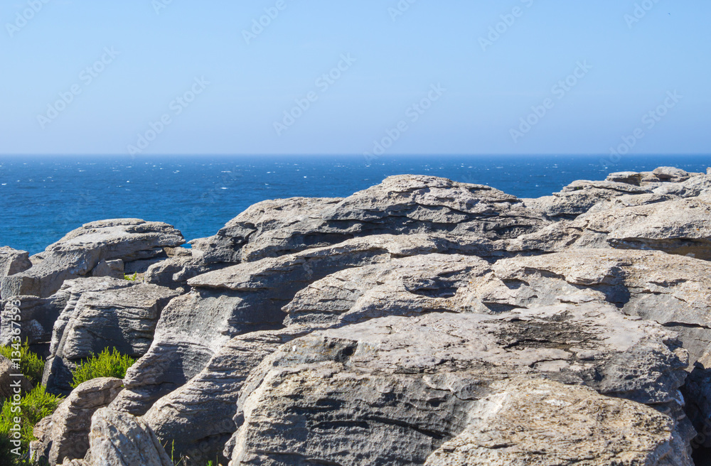 Large formation of rocks, stone on shoreline between beach and ocean in portugal background , Rock beach.