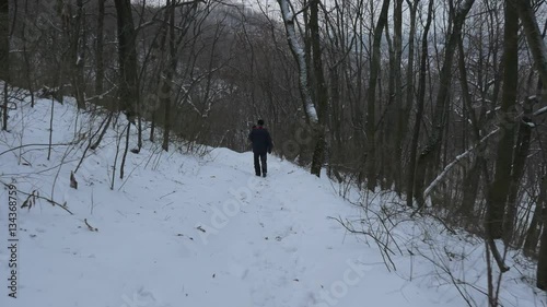 the National Park of Sviatogorskaya Orthodox Lavra and a Religious Bearded Man Walking Along Its Slopes Covered With Deep Snow and Bare Trees photo