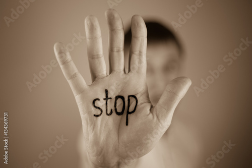 man showing  the word "stop" written on the palm of a his hand