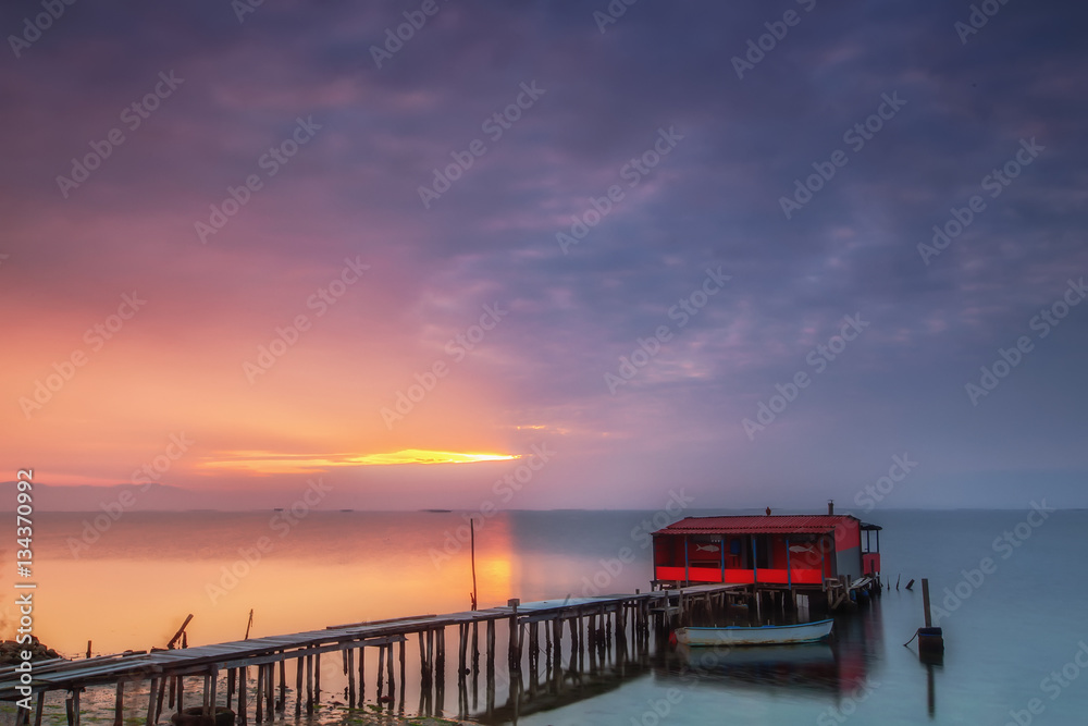 Long exposure of magic sunrise over the ocean with a hut in the