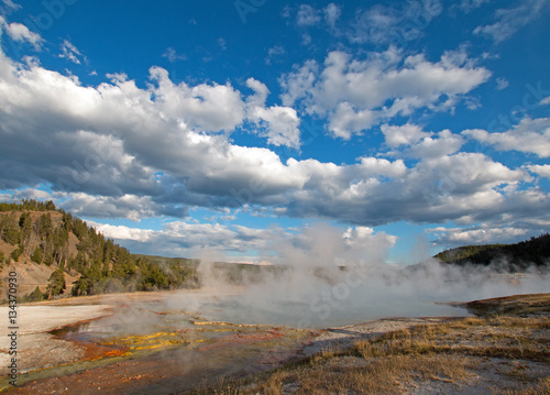 Excelsior Geyser under afternoon cloudscape in the Midway Geyser Basin next to the Firehole River in Yellowstone National Park in Wyoming USA