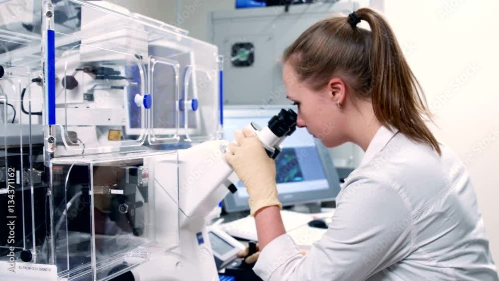 Young scientist looking through an electronic microscope