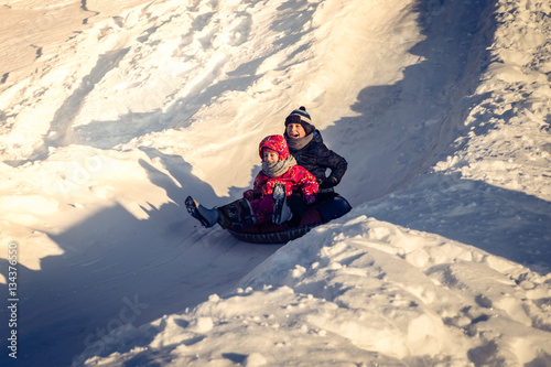 children sliding down on snow tubes