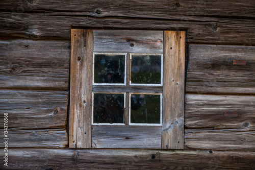Square window of old one-storey wooden house in the North