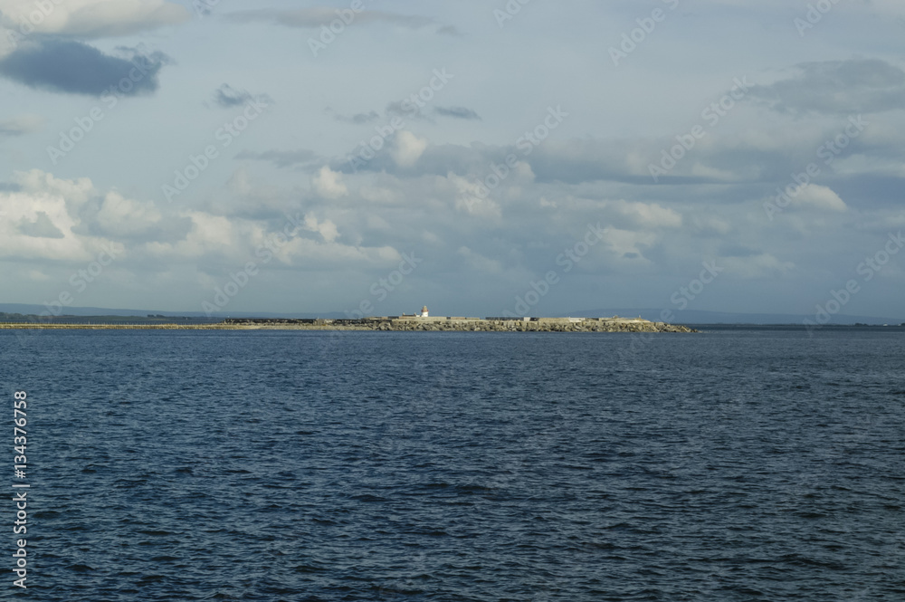 Island wih lighthouse in sea.