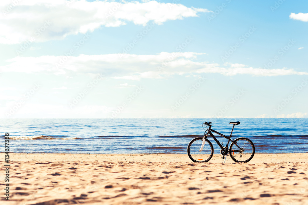 One bicycle standing on the beach sand on blue seascape backgrou
