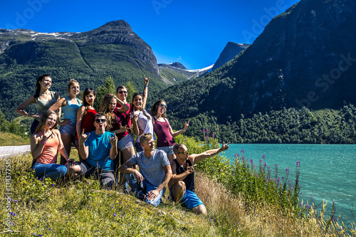 Group of young people standing next to the beautiful lake among