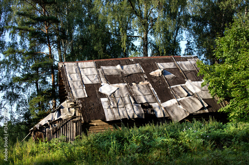 Old building with decaying ruberoid roofing half replaced with new one. photo