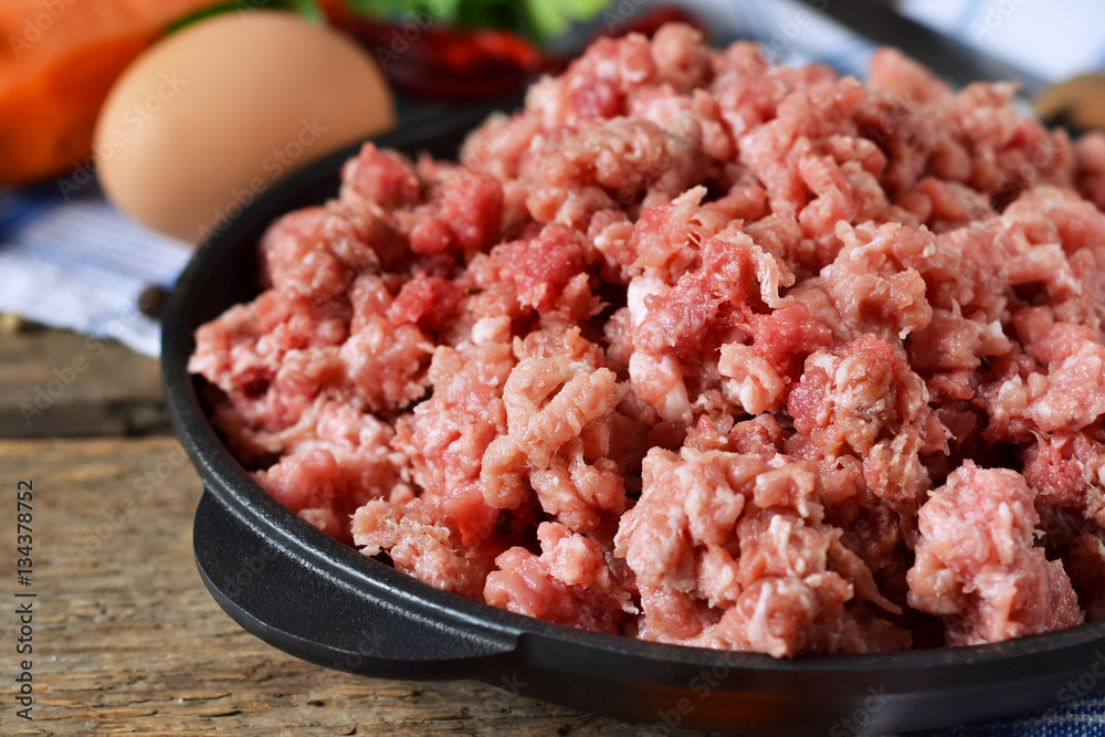 Raw beef in a cast iron frying pan on a wooden background Raw beef in a cast iron frying pan on a wooden background